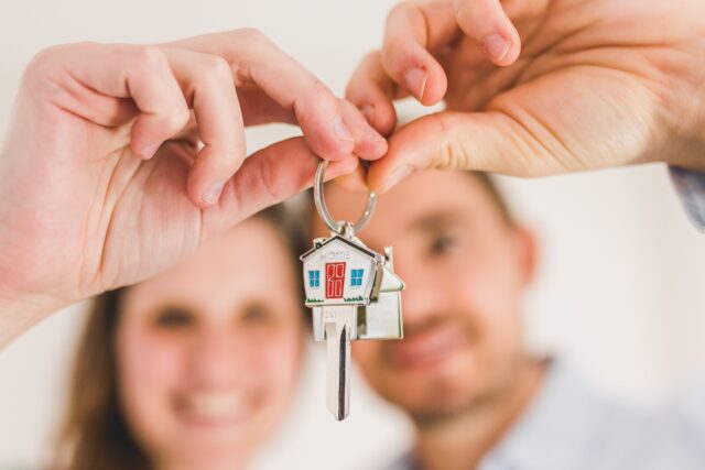 A woman and a man holding a keychain with a house on it